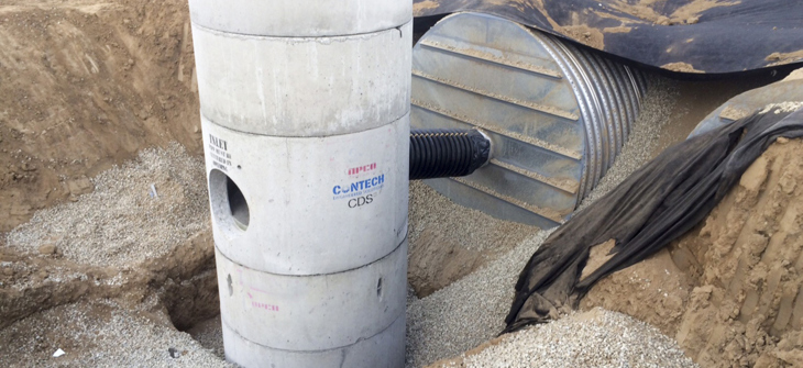 A CDS hysrodynamic separator and corrugated metal pipe installed in a gravel trench at a construction site.