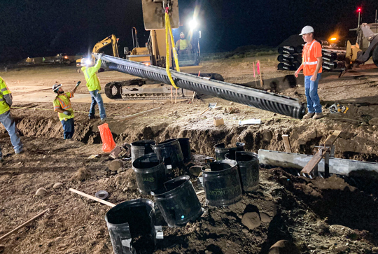 Installation of slotted drain pipe at night. 