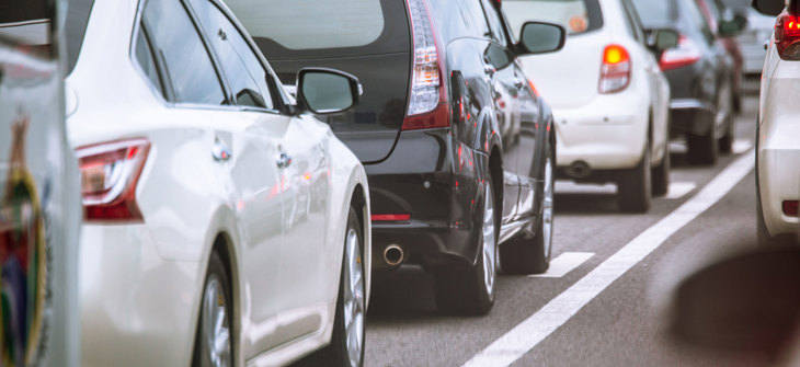 Line of cars in traffic on a highway, with white and black vehicles visible in the foreground.