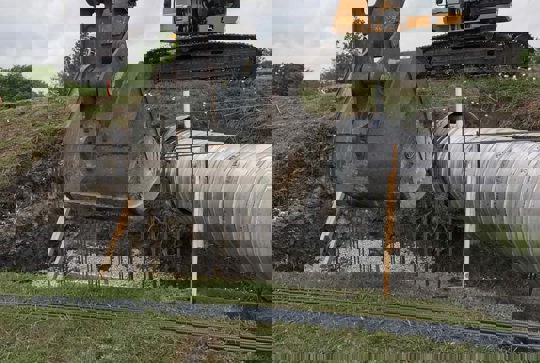 Relining a culvert with corrugated metal pipe. 