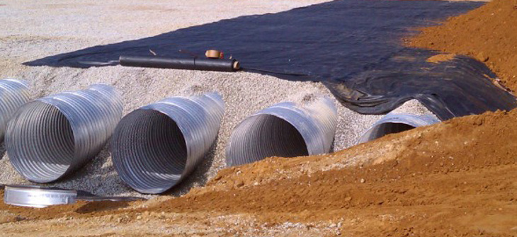 A corrugated metal pipe stormwater detention system is under construction.