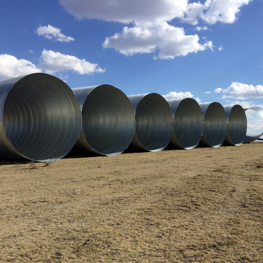 Large diameter corrugated steel pipe staged for installation. 
