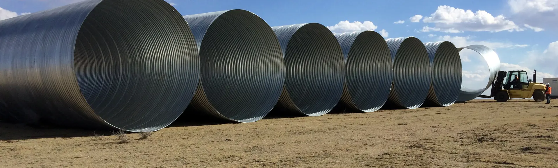 Large diameter corrugated metal drainage pipe staged for installation.