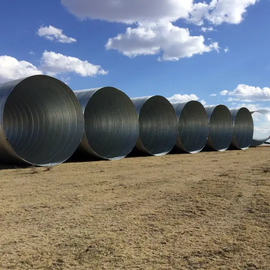 Large diameter corrugated steel pipe staged for installation.