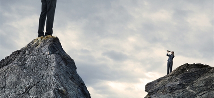 Two men in suits stand on separate rocky peaks, each looking through telescopes at each other under a cloudy sky.