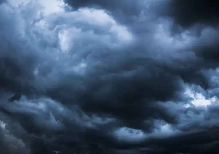 Dark, dense storm clouds cover the sky, creating a dramatic and moody atmosphere.