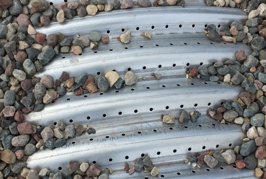 Perforated corrugated metal pipe with backfill.