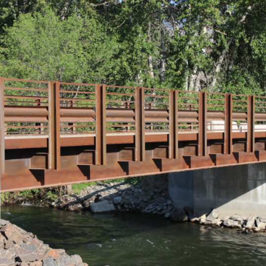Big R steel rolled girder bridge over a river. 