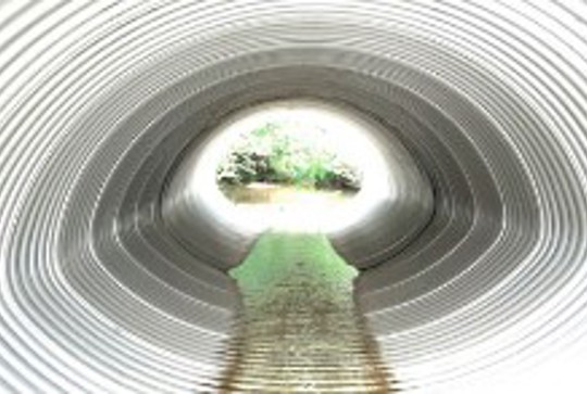 A low profile, low drop culvert made from corrugated metal pipe. 